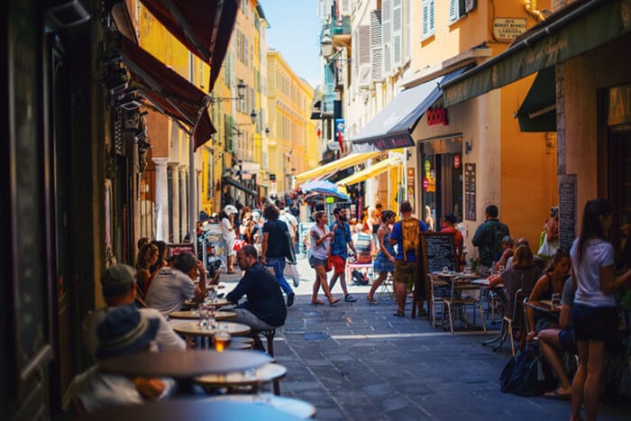 A busy pedestrian street with people sitting in cafes