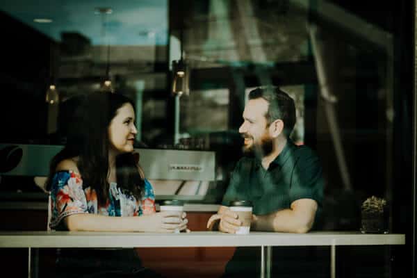 A man and woman talking at a coffee shop.