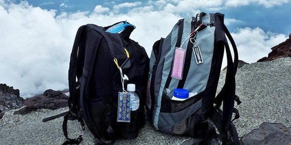 Two backpacks with Japanese good luck charms hanging from them