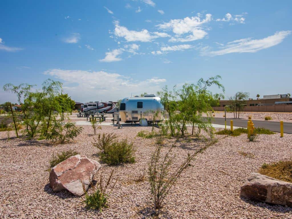 A silver camping trailer behind plants