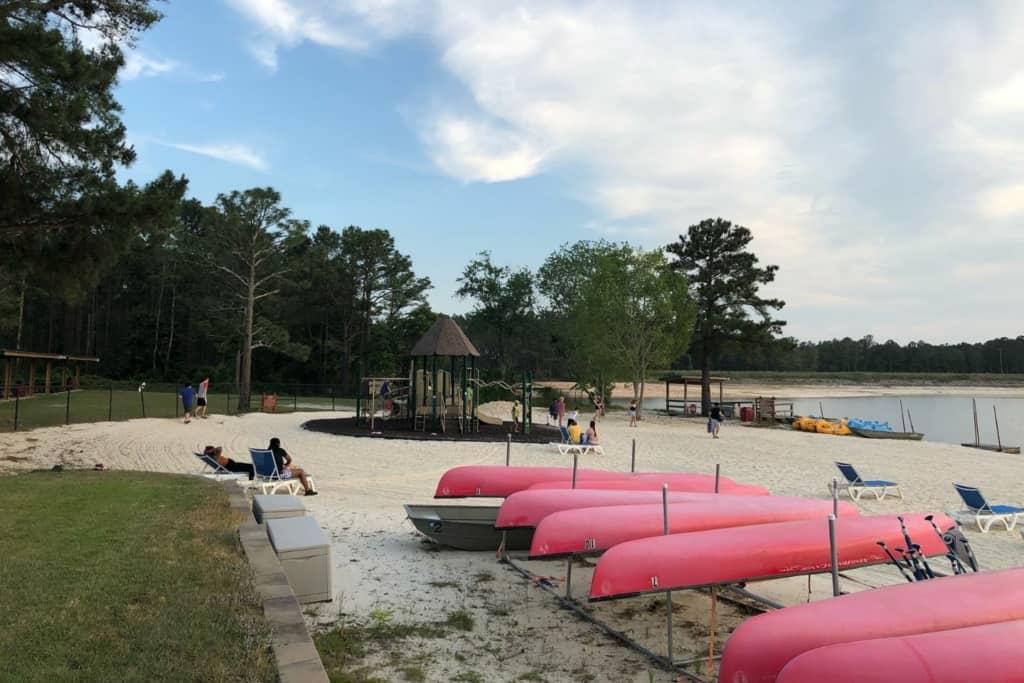 red canoes stored upside down near a beach and a playground