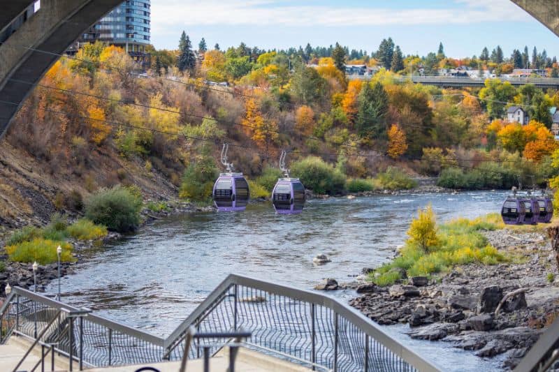 Cable cars over a river with fall foliage in the background