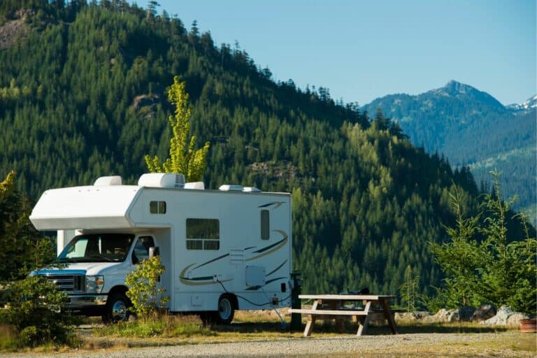 An RV parked next to a forested mountain