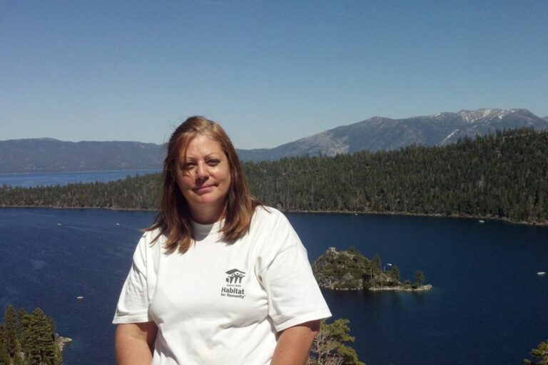 A woman in a white t-shirt sitting in front of Lake Tahoe