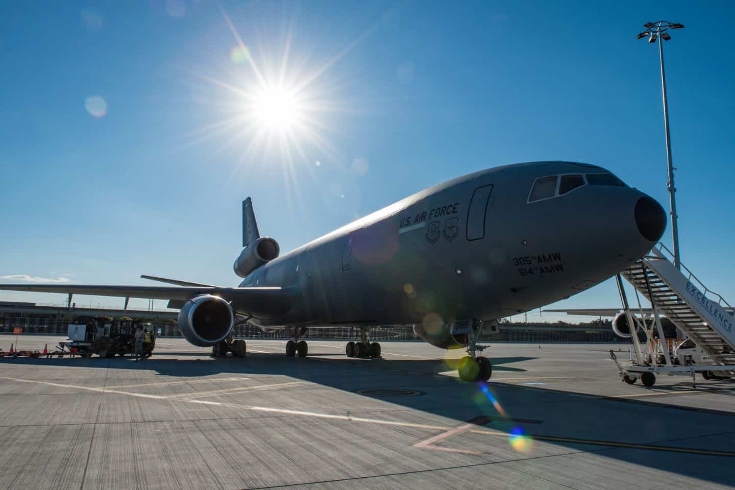 A military aircraft on the tarmac with rolling stairs outside.