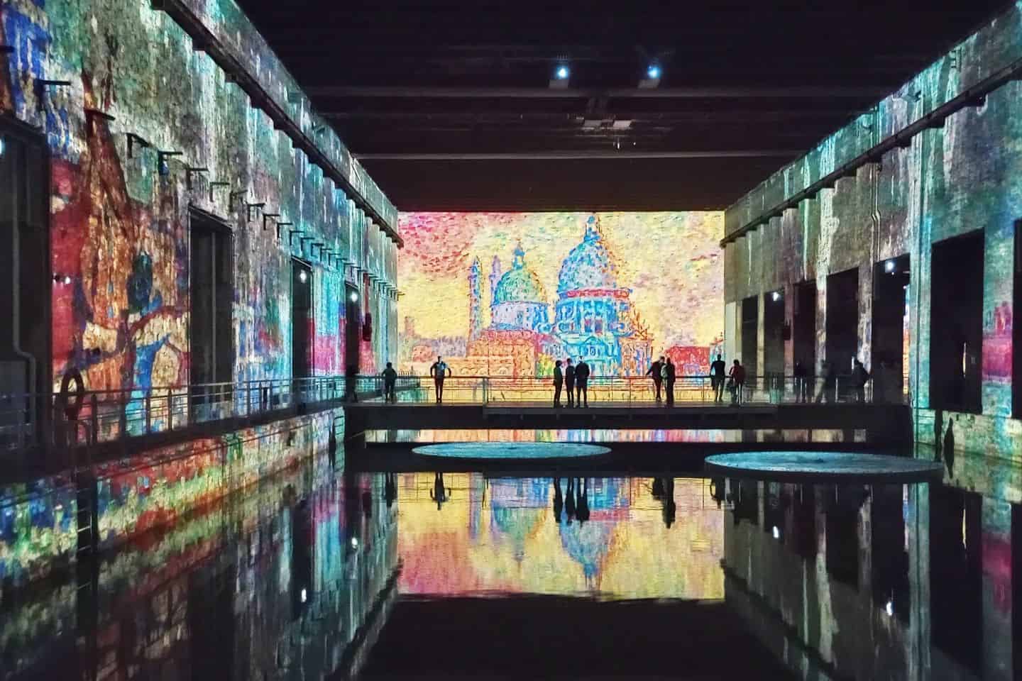 Colorful artwork reflecting on water in a dark venue