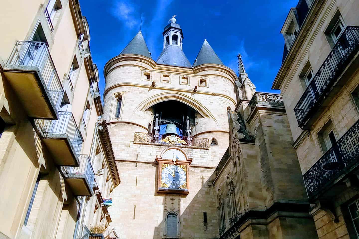 A stone clock tower with a bell above it