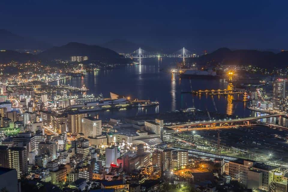 Night view of a city with mountains and ocean in the background