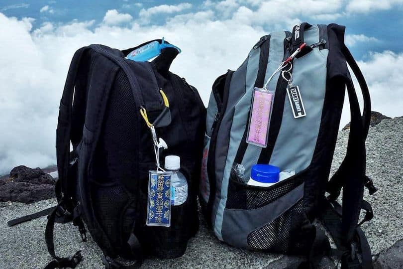 Two backpacks with Japanese good luck charms hanging from them