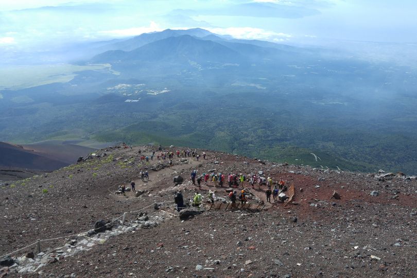 A hiking path with many hikers and mountains in the distance