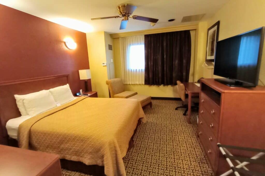 A hotel room with bed, chair, and desk