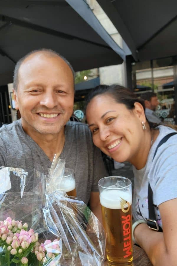 A man and woman leaning in for a photo with beers in front of them.