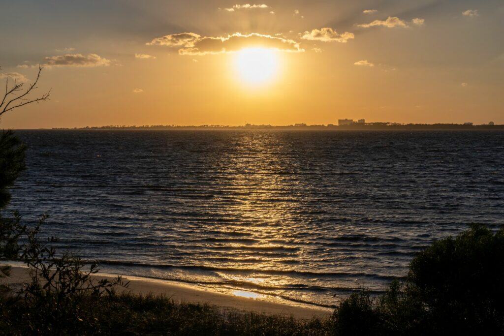 Sunset seen from the beach with buildings on the horizon