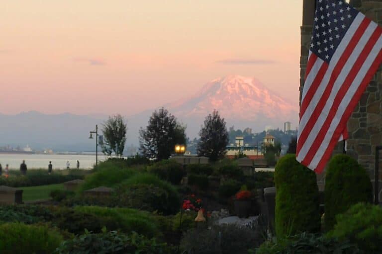 A US flag with snow-capped Mt. Rainier in the background.