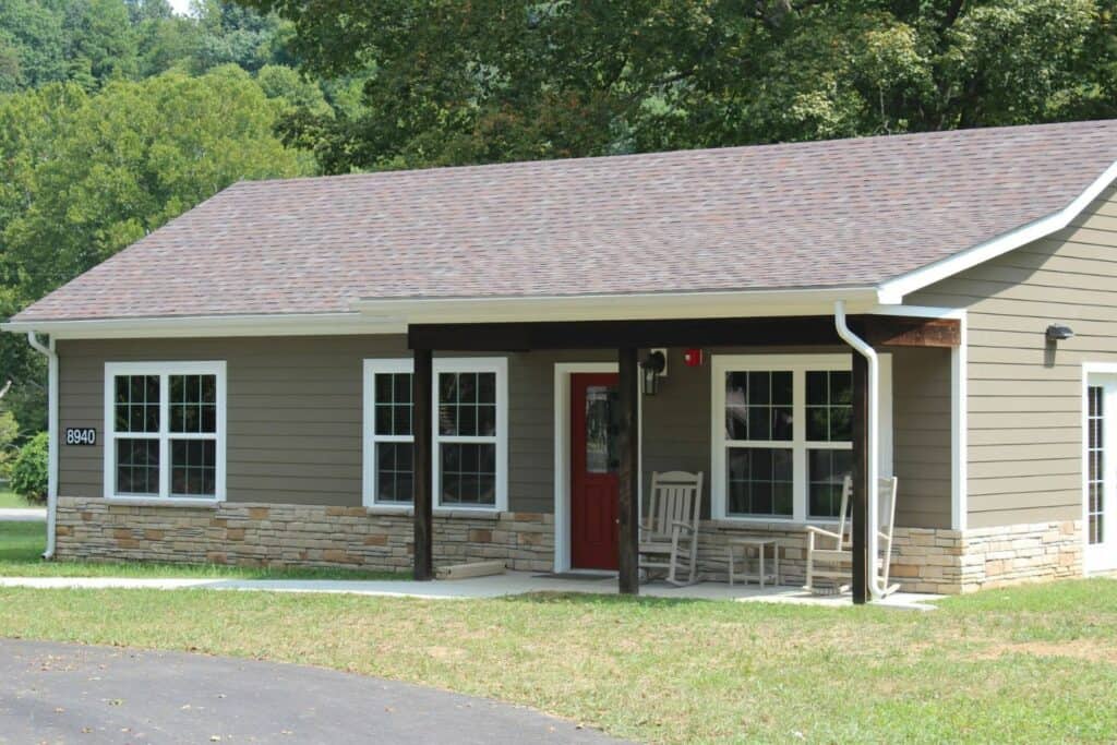 A large cabin with rocking chairs in front