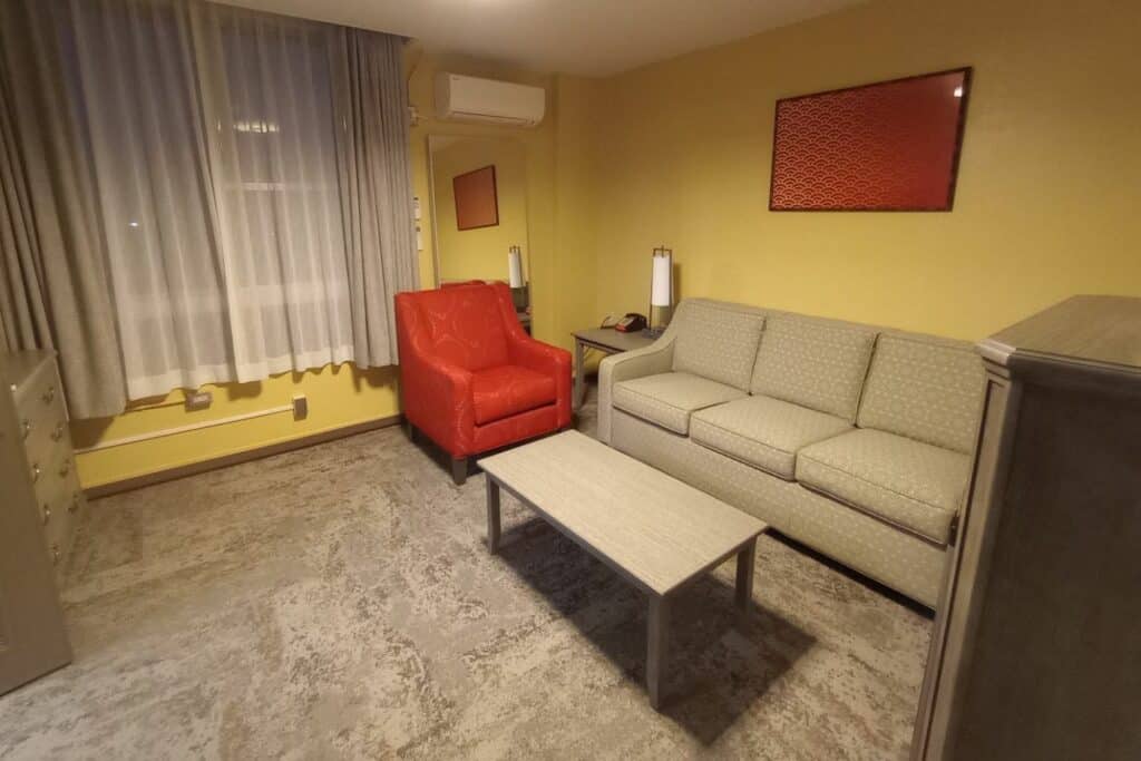 A room with a gray couch and orange chair