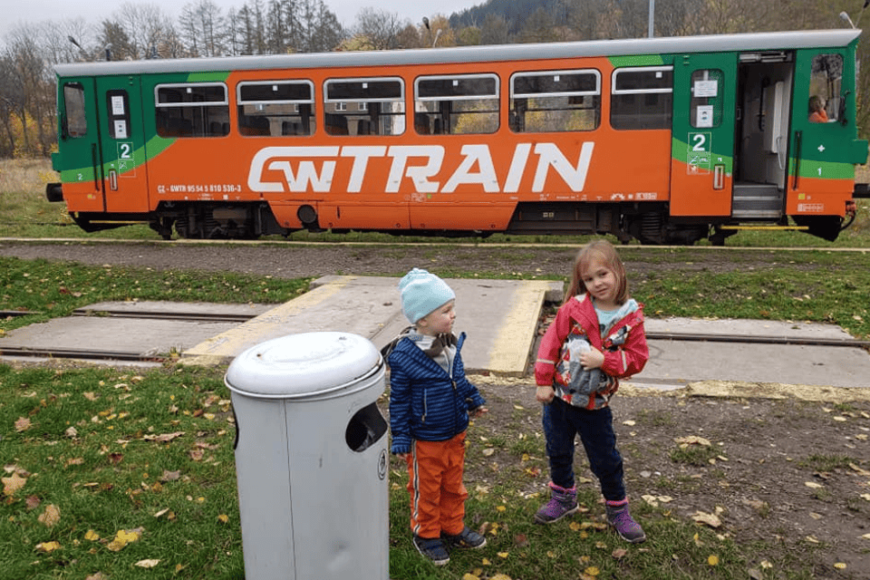 two young children next to an orange and green train