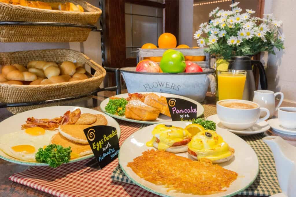 Plate of breakfast food, including pancakes and eggs plus eggs benedict with hashbrowns