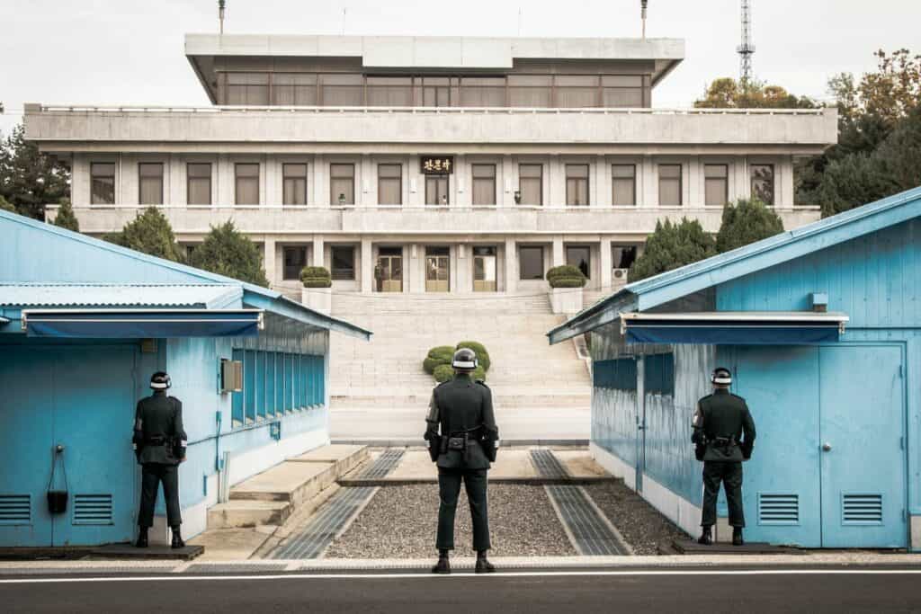 Korean soldiers with their backs to the camera guarding a building