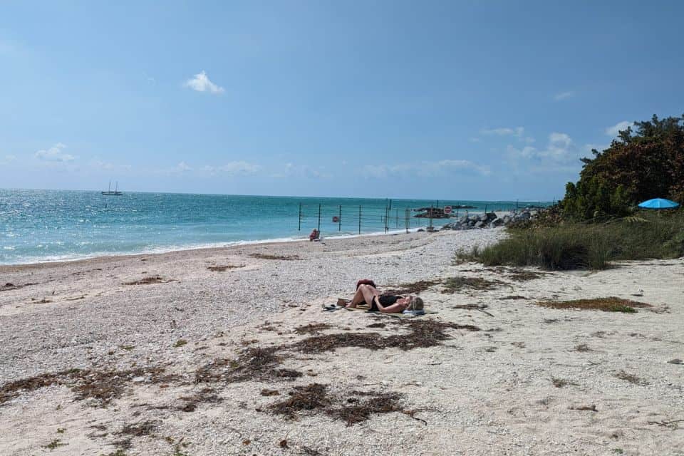 A beach with one person sunbathing