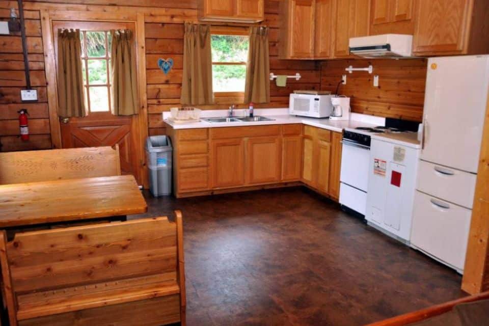A full kitchen with booth and benches in a log cabin