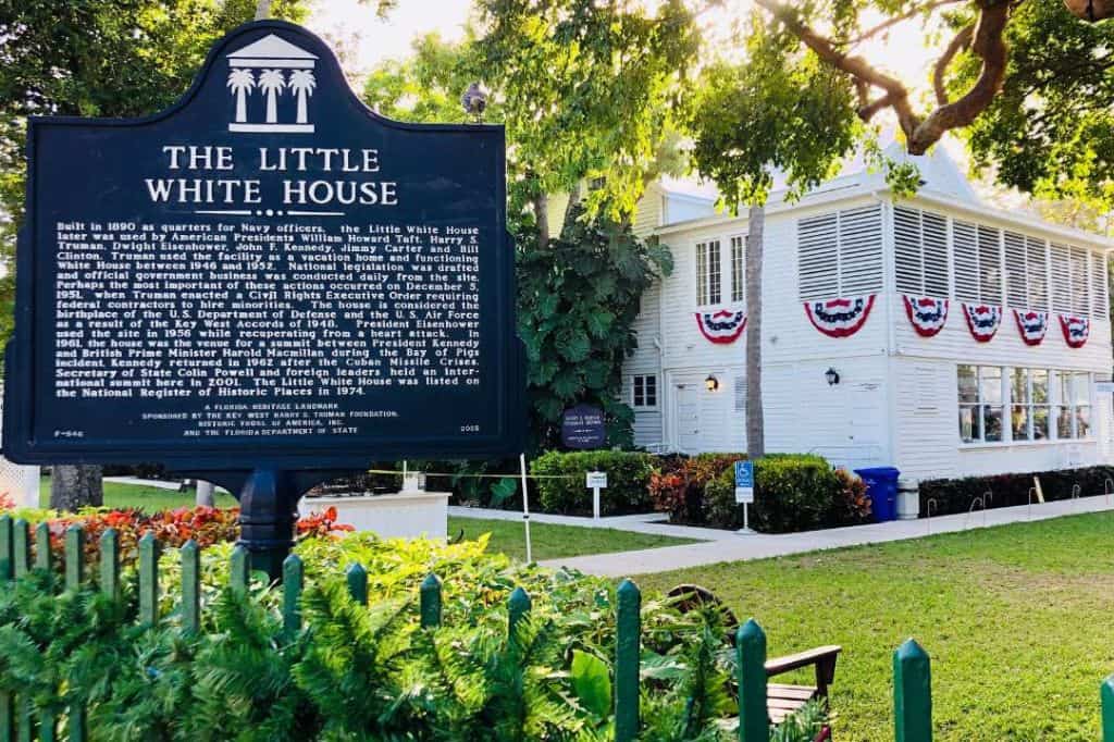 a small white house with a sign in front that explains the house's history