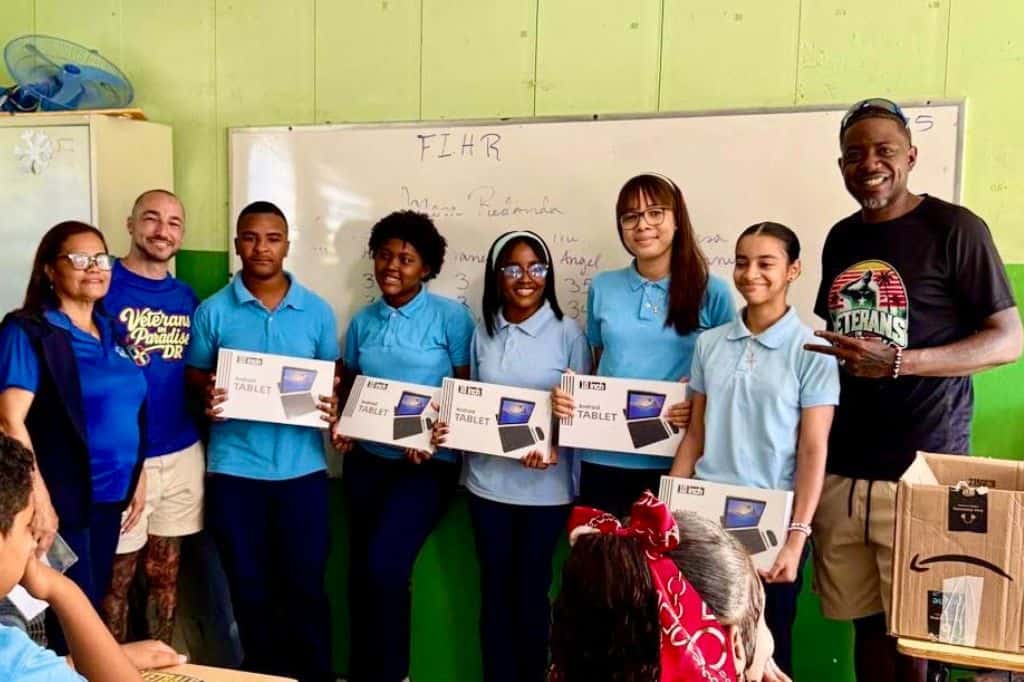 Veterans and students posing in a classroom after a tablet donation.