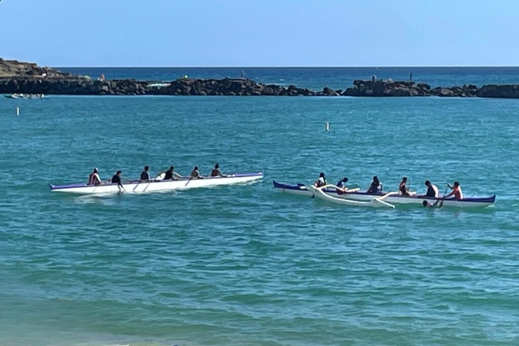 two outrigger canoe teams paddle across the turquoise waters of Pokai Bay on Oahu’s west side.