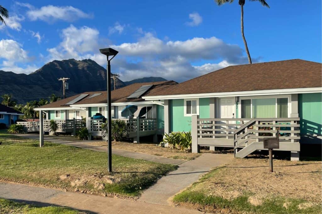 Row of mint-green Pililaau Army Recreation Center cabins with mountain backdrop on Oahu’s west coast.