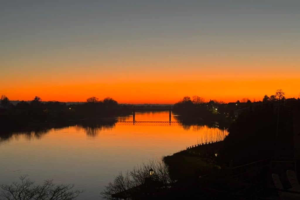 Brilliant orange sunset reflecting on the Dordogne River in Castillon-la-Bataille, France”