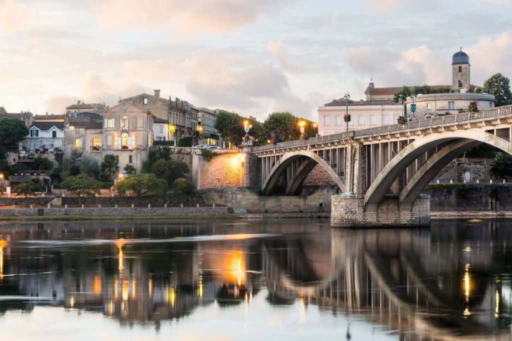 Evening view of Castillon-la-Bataille with its arched bridge reflecting on the Dordogne River