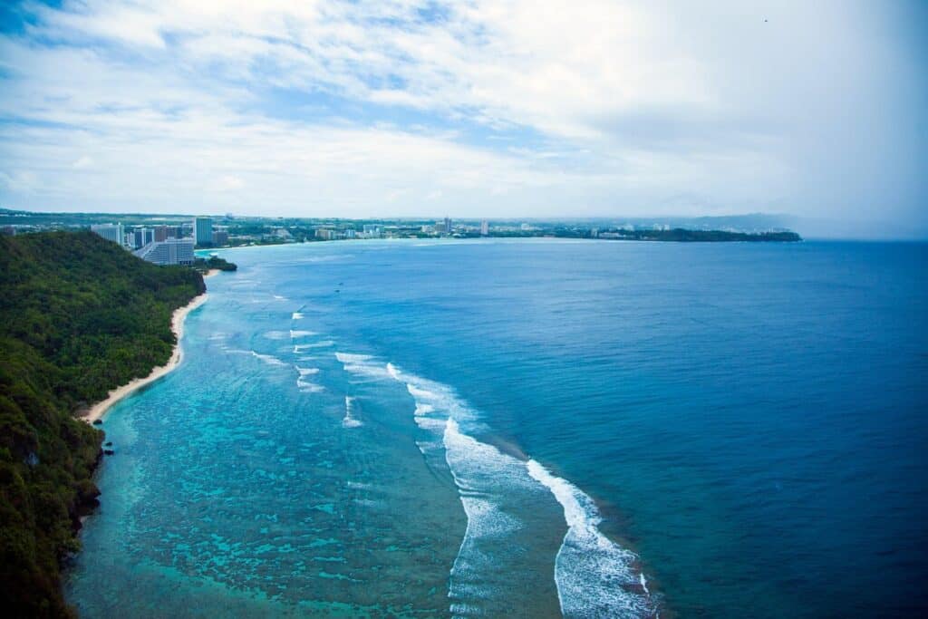 Guam’s coastline with hotel towers lining Tumon Bay, seen from a high cliff