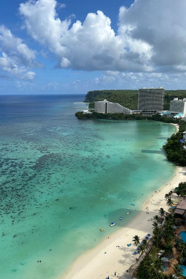 View of the turquoise waters and white sand beach in Tumon Bay, Guam, with high-rise beachfront resorts