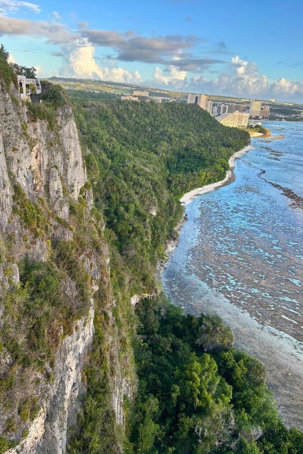 Dramatic view from Two Lovers Point in Guam, with limestone cliffs, reef-filled waters, and Tumon’s skyline in the distance.
