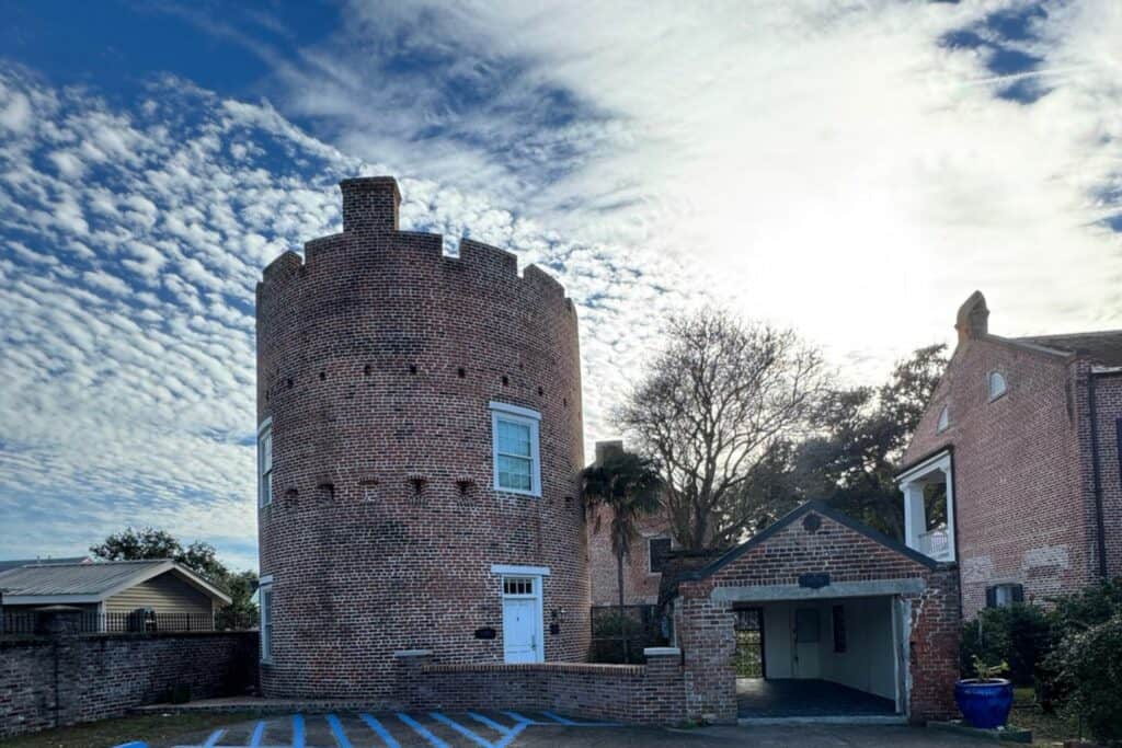 Brick exterior of historic Jackson Barracks building with round tower and courtyard entrance.