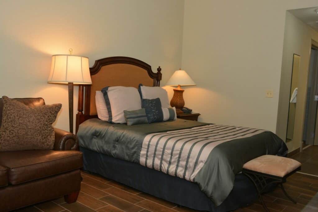 Queen bed guest room at Jackson Barracks with seating area and bedside lamps.