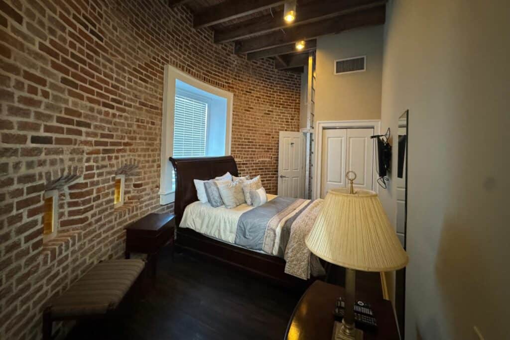 Bedroom in Jackson Barracks East Tower with exposed brick walls and wood beam ceiling.
