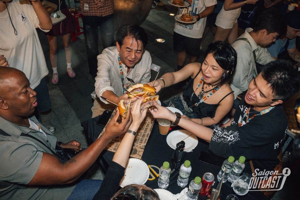 Markeiz sharing oversized burgers with friends at a crowded food event.