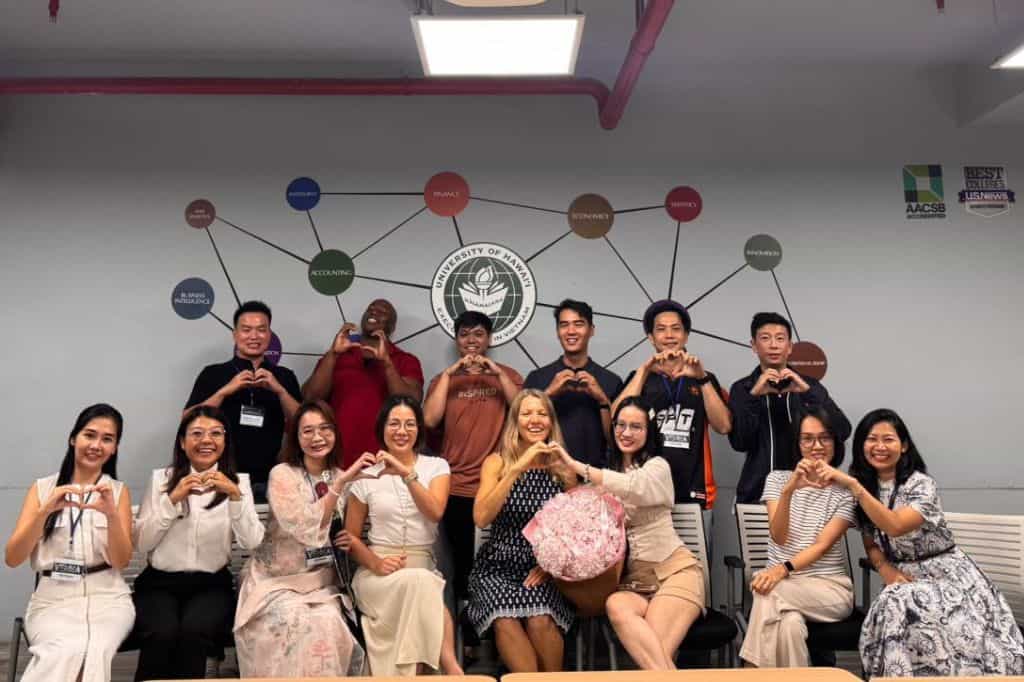Fourteen men and women from different backgrounds posing with their hands making a heart shape