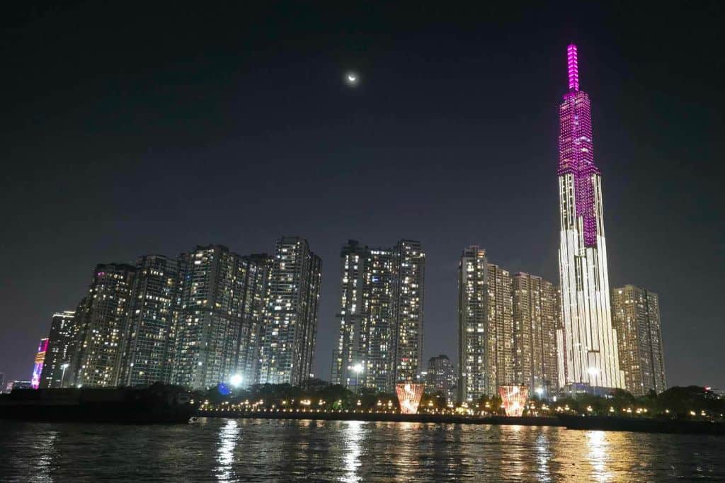 Ho Chi Minh City skyline at night with Landmark 81 illuminated in pink and white above the Saigon River.