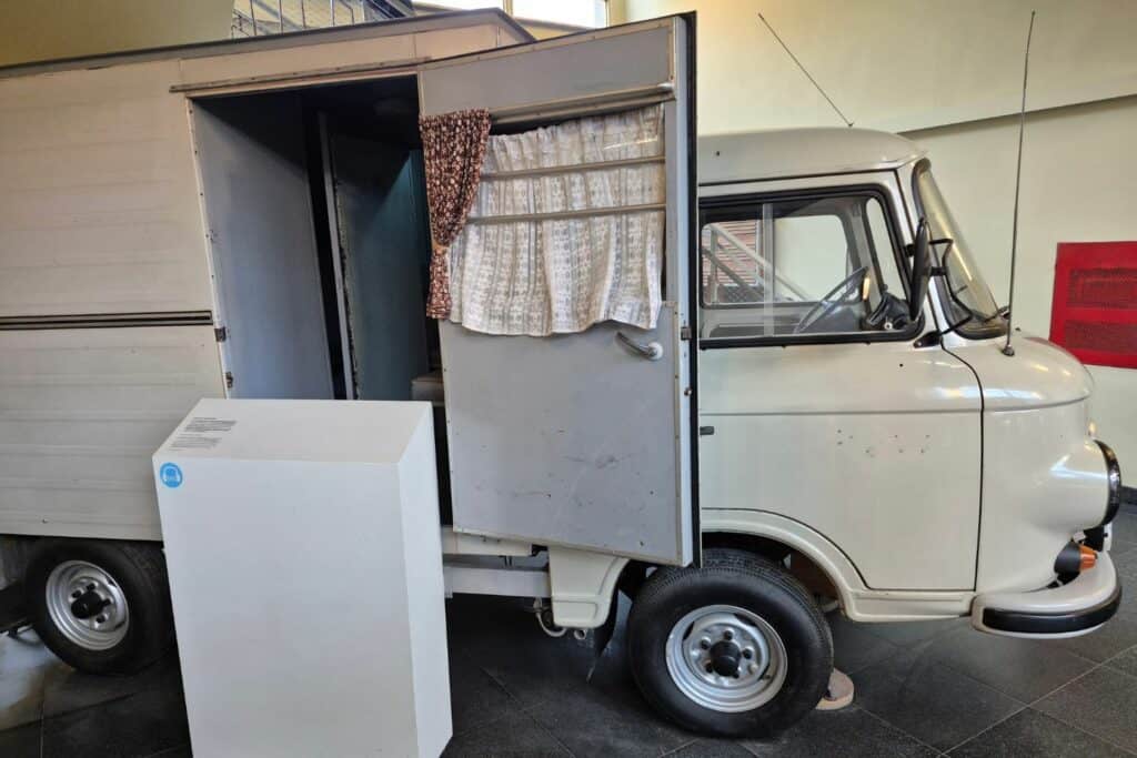 Vintage prisoner transport van with small compartment displayed inside a museum