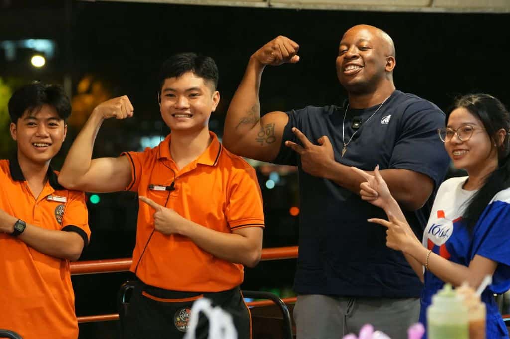 Markeiz comparing biceps muscles with staff at a local restaurant