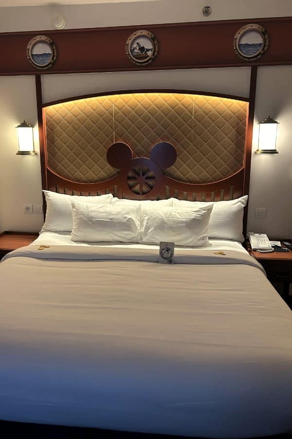 A hotel bed with Mickey Mouse ears on the headboard.