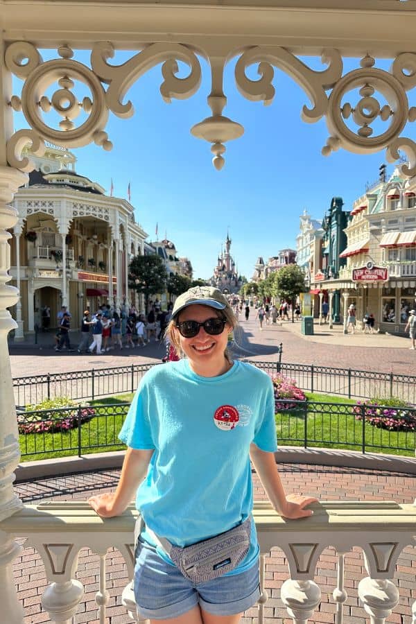 girl in a turqoise t-shirt standing in front of Main Street USA at Disneyland Paris with the castle in the background