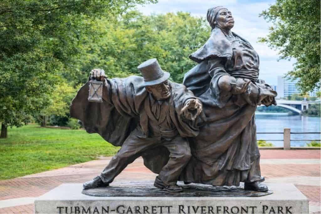 A bronze statue of a woman and a man in a riverfront park