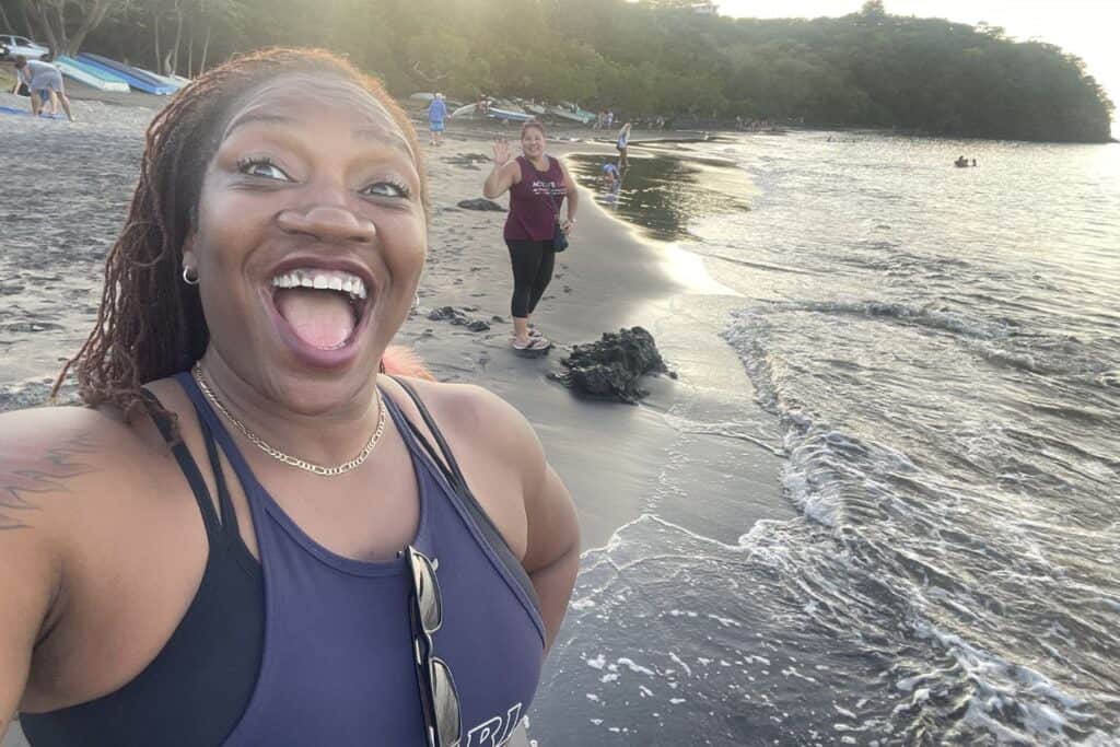 Isah takes a playful selfie with a friend walking along the shoreline at Playas del Coco
