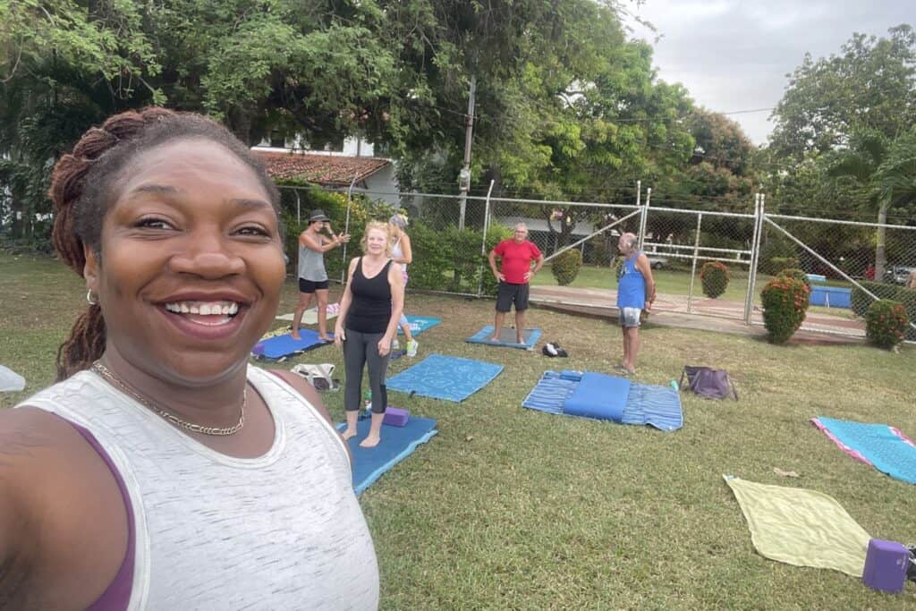 Isah smiles in front of an outdoor yoga class on a lawn in Costa Rica.