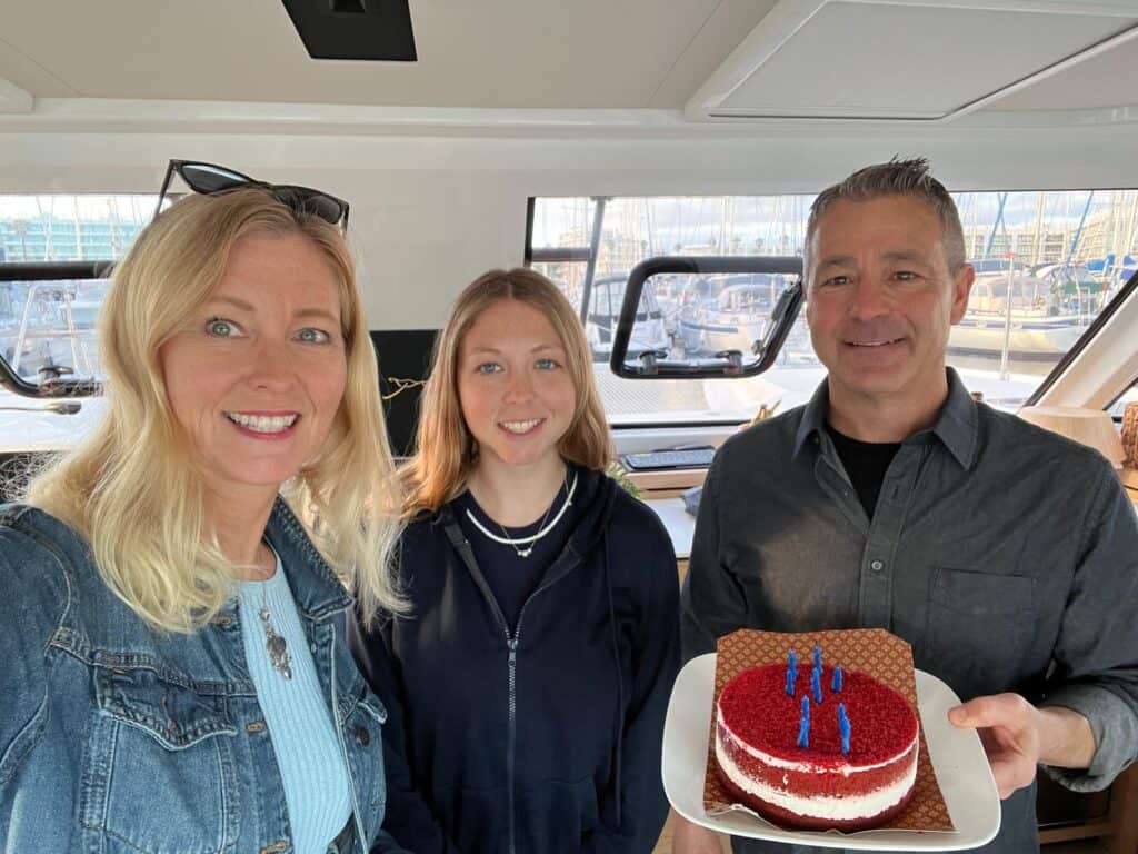 Dan, Paula, and their daughter aboard their catamaran with a birthday cake