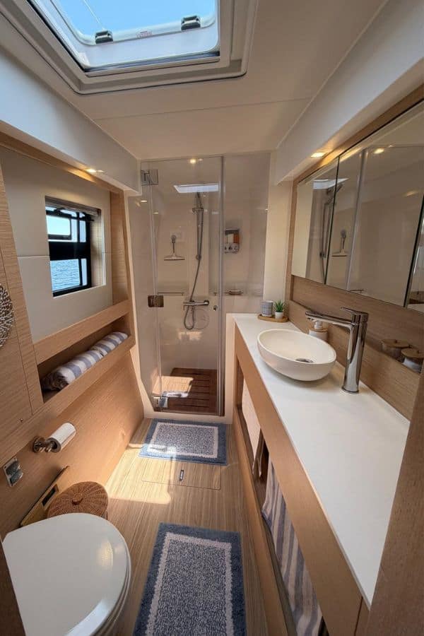 Catamaran bathroom with shower, sink, toilet, and overhead hatch