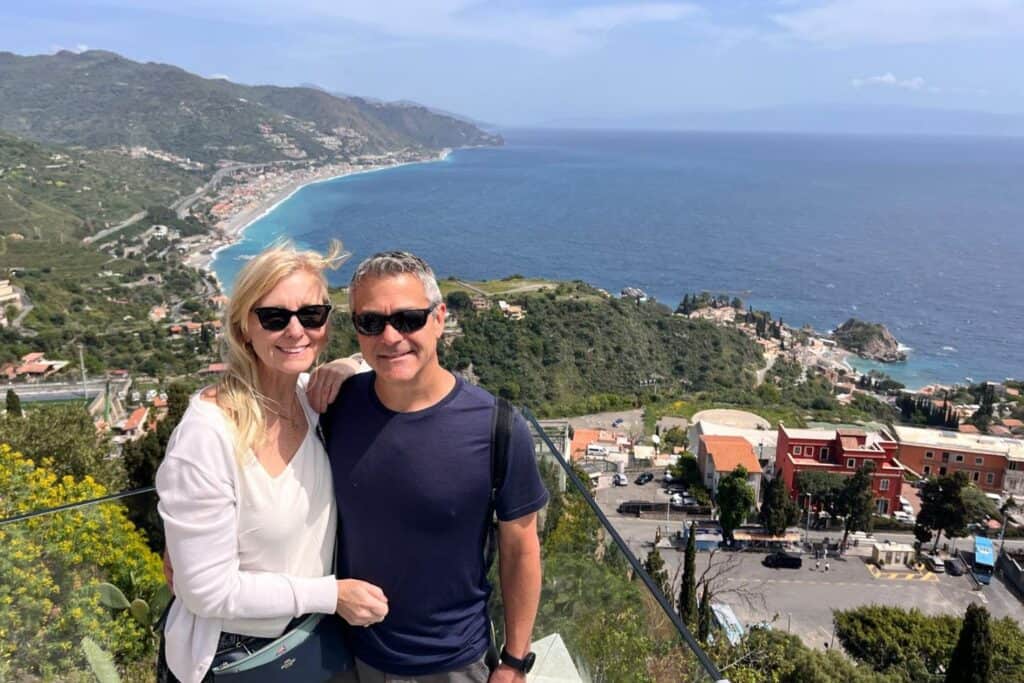 Dan and Paula standing above a Mediterranean coastline during a hike